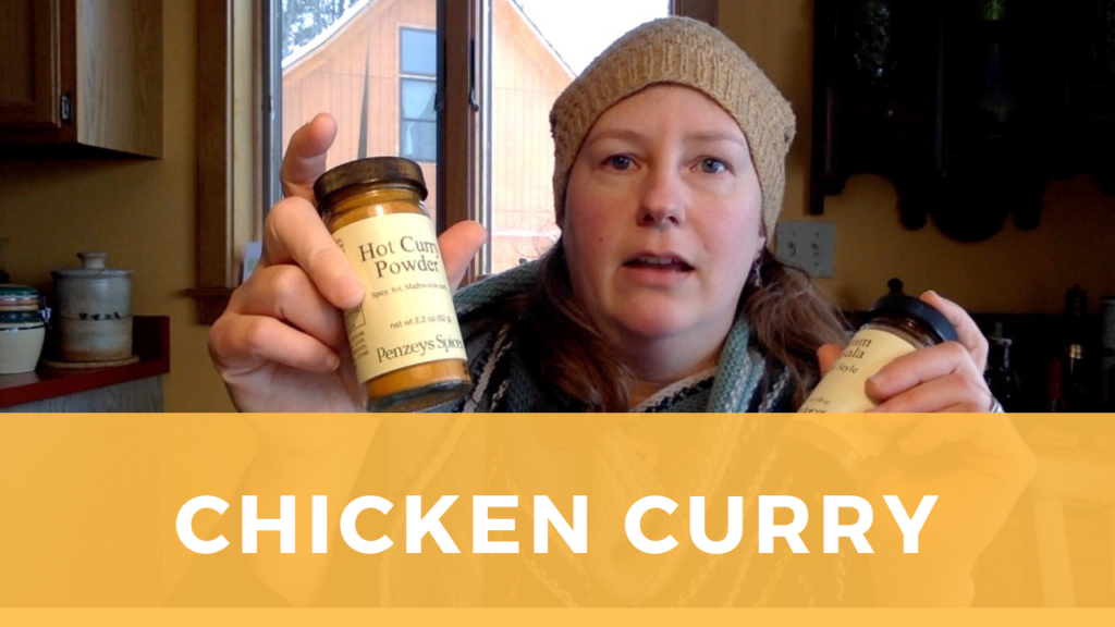 Sarah is holding up two jars of different types of curry powder.